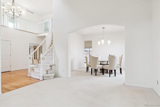 dining area featuring carpet flooring, a towering ceiling, and a notable chandelier