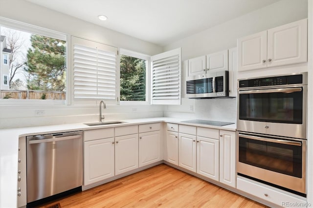 kitchen featuring sink, white cabinets, stainless steel appliances, and light hardwood / wood-style floors