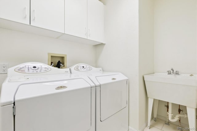 laundry area featuring separate washer and dryer, light tile patterned floors, and cabinets