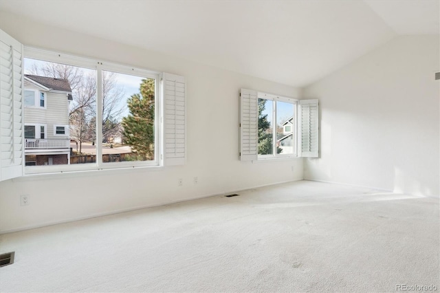 spare room featuring carpet, a healthy amount of sunlight, and lofted ceiling