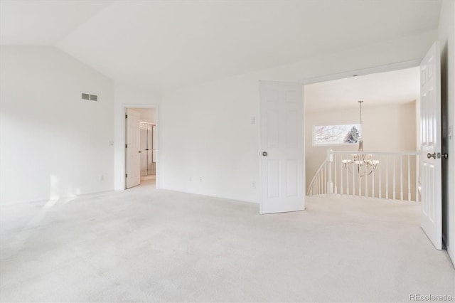 carpeted empty room featuring a chandelier and lofted ceiling