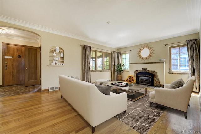 2285 N Monaco Pkwy, Denver, CO 80207 - living room with wood finished floors, arched walkways, a glass covered fireplace, crown molding, and baseboards