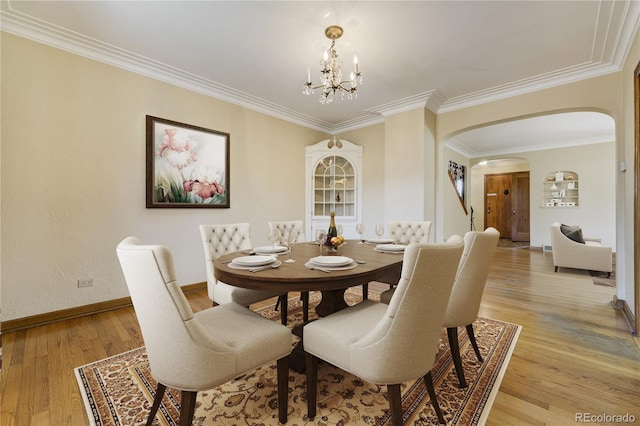 2285 N Monaco Pkwy, Denver, CO 80207 - dining space with arched walkways, light wood-style flooring, a chandelier, baseboards, and ornamental molding