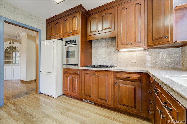 2285 N Monaco Pkwy, Denver, CO 80207 - kitchen with freestanding refrigerator, stainless steel oven, light wood-type flooring, brown cabinetry, and crown molding