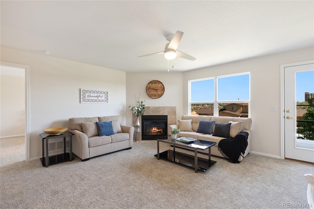 carpeted living room with ceiling fan and a tiled fireplace