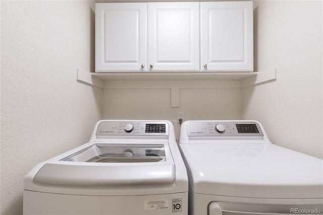 washroom featuring cabinets and washer and clothes dryer