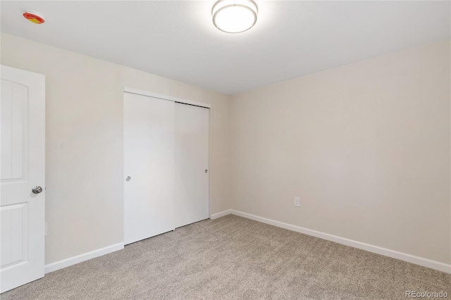 unfurnished bedroom with light carpet and a closet