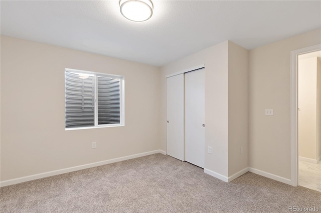 unfurnished bedroom with a closet and light colored carpet