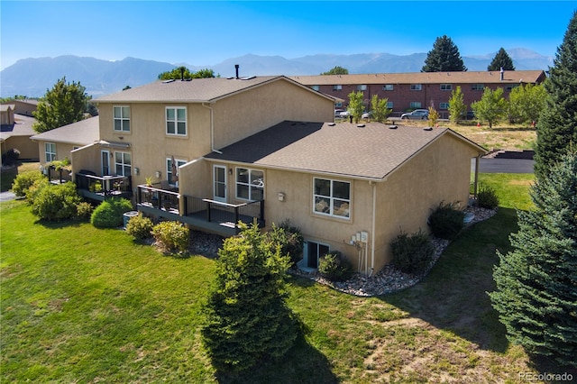 back of property featuring a yard and a deck with mountain view