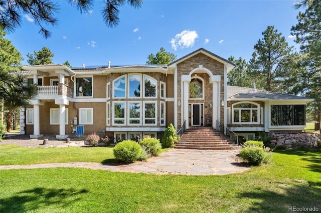 rear view of house featuring a balcony and a yard