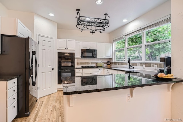 7420 S Houstoun Waring Cir, Littleton, CO 80120 - kitchen with black appliances, light wood-style floors, white cabinets, dark stone countertops, and recessed lighting