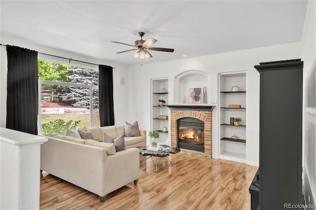 7420 S Houstoun Waring Cir, Littleton, CO 80120 - living room with a fireplace, ceiling fan, light wood-style floors, and built in shelves