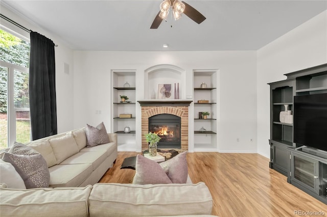 7420 S Houstoun Waring Cir, Littleton, CO 80120 - living area with a ceiling fan, built in features, a brick fireplace, and light wood-style flooring