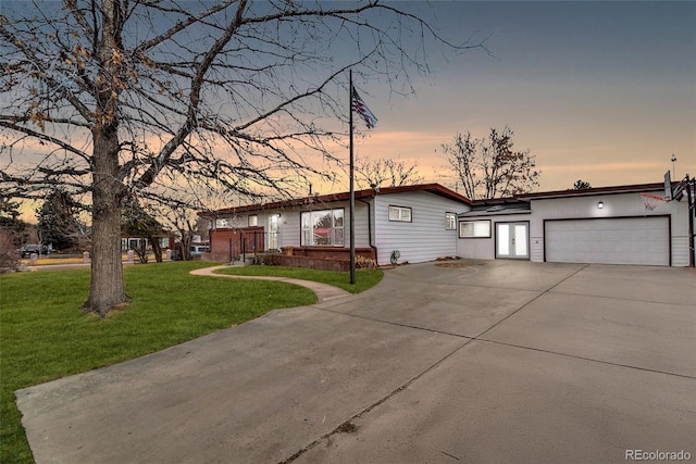 view of front of house featuring concrete driveway, brick siding, a lawn, and an attached garage