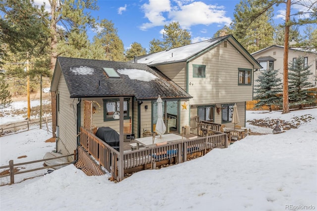 snow covered back of property featuring a wooden deck