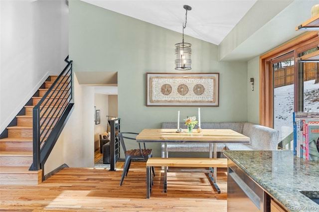 dining room featuring breakfast area, lofted ceiling, light hardwood / wood-style flooring, and a notable chandelier