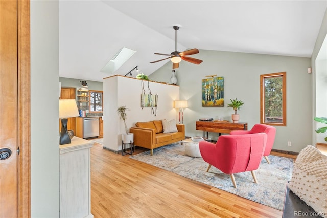 living room with ceiling fan, wood-type flooring, and lofted ceiling with skylight