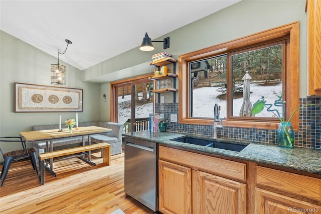 kitchen featuring vaulted ceiling, tasteful backsplash, sink, stainless steel dishwasher, and light wood-type flooring