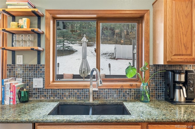 kitchen featuring tasteful backsplash, stone countertops, and sink