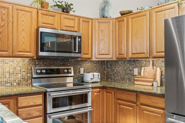 kitchen with backsplash, stainless steel appliances, and dark stone counters