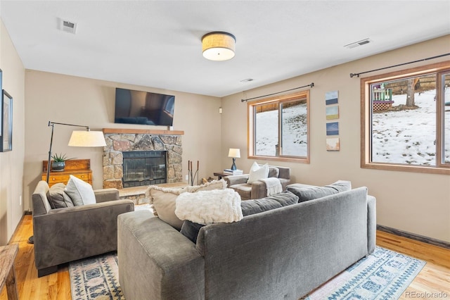 living room with a stone fireplace and light wood-type flooring