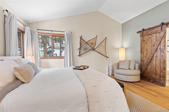 bedroom featuring vaulted ceiling, a barn door, and hardwood / wood-style floors