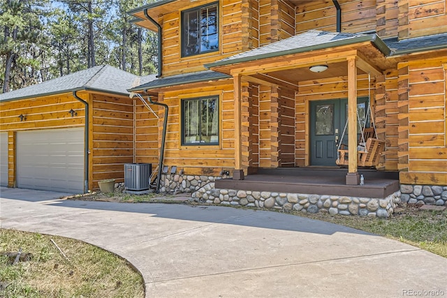 doorway to property with covered porch, a garage, and central AC