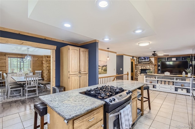 kitchen with ceiling fan, decorative light fixtures, light stone countertops, and stainless steel gas range