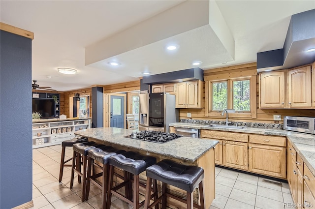 kitchen featuring a kitchen island, a kitchen bar, stainless steel appliances, sink, and ceiling fan