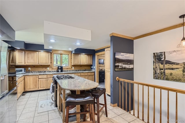 kitchen with appliances with stainless steel finishes, a center island, decorative backsplash, hanging light fixtures, and light stone counters