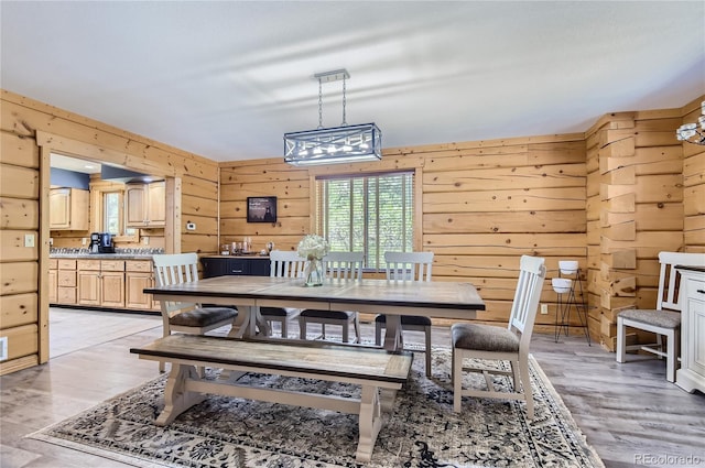 dining area with light wood-type flooring and wooden walls