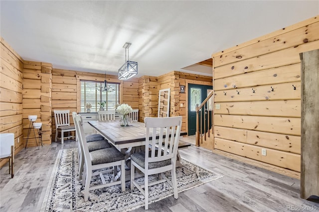 dining room featuring a chandelier, hardwood / wood-style flooring, and wooden walls