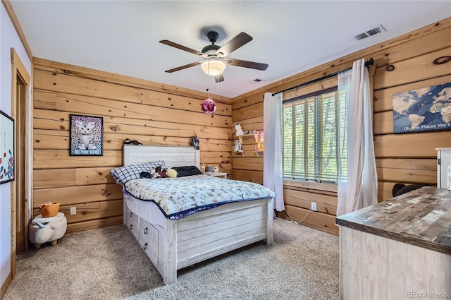 carpeted bedroom featuring ceiling fan and wood walls