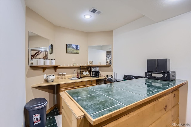 bar featuring tile countertops, dark tile patterned flooring, and sink