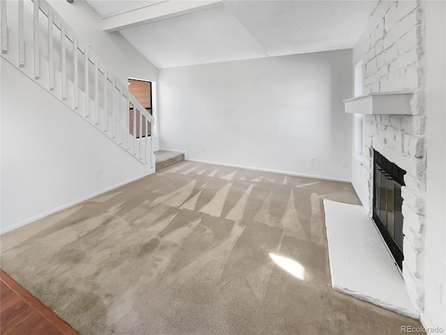 unfurnished living room with light carpet, a fireplace, and lofted ceiling with beams