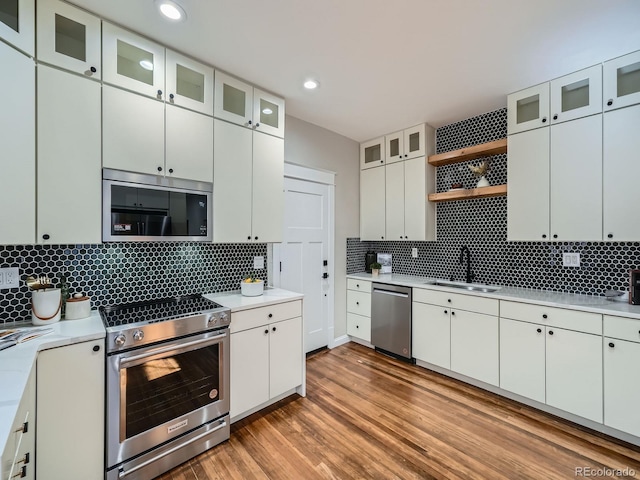 kitchen with open shelves, light wood-style flooring, a sink, stainless steel appliances, and light countertops