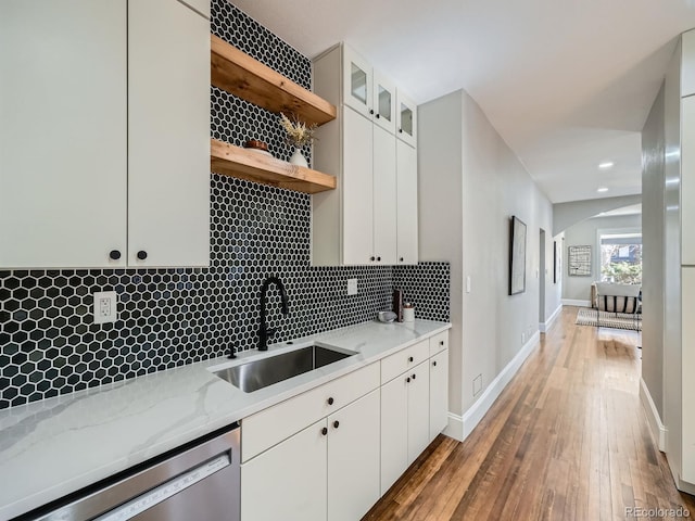 kitchen featuring open shelves, a sink, wood-type flooring, dishwasher, and backsplash