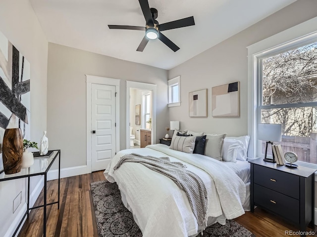 bedroom featuring dark wood finished floors, a ceiling fan, baseboards, and connected bathroom