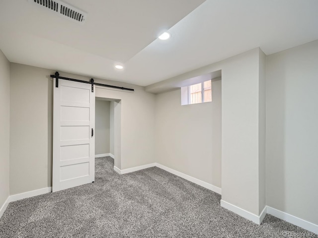 below grade area featuring visible vents, baseboards, and a barn door