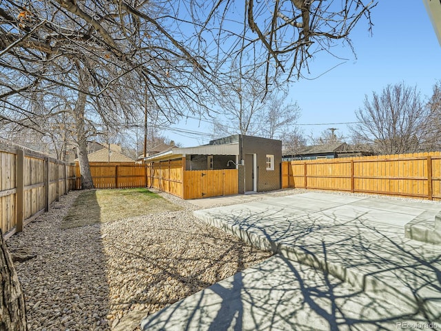 view of yard featuring a patio, an outdoor structure, and a fenced backyard