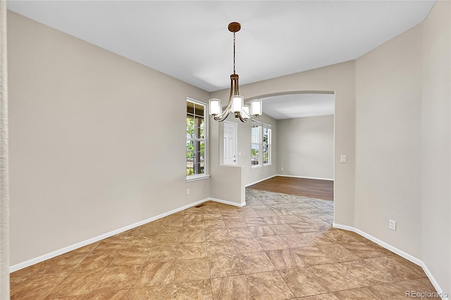 16500 Hitching Post Cir, Parker, CO 80134 - empty room featuring a chandelier, arched walkways, and light stone finish floors