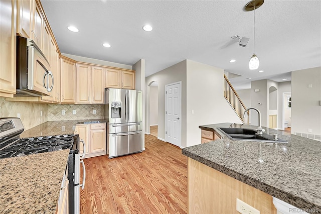 16500 Hitching Post Cir, Parker, CO 80134 - kitchen with stainless steel appliances, arched walkways, light brown cabinets, light wood finished floors, and decorative backsplash