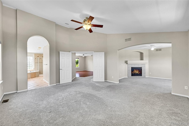 16500 Hitching Post Cir, Parker, CO 80134 - unfurnished living room featuring ceiling fan, carpet, arched walkways, a fireplace, and high vaulted ceiling