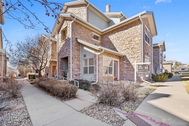 view of property exterior featuring stone siding and a chimney