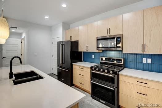 kitchen with light brown cabinetry, sink, appliances with stainless steel finishes, and tasteful backsplash