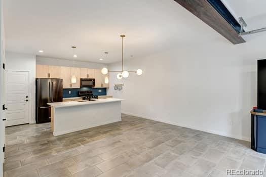 kitchen with light hardwood / wood-style flooring, an island with sink, hanging light fixtures, stainless steel appliances, and sink