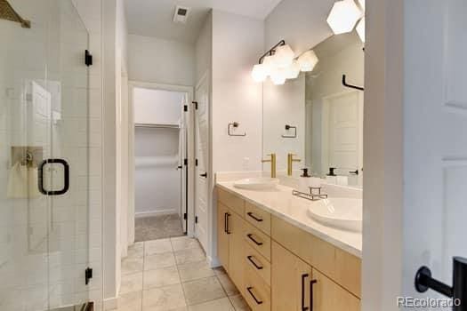 bathroom featuring a shower with door, tile patterned flooring, and vanity