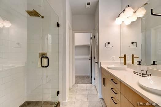 bathroom featuring vanity, a shower with shower door, and tile patterned floors