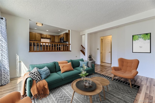 living area with stairway, light wood-type flooring, and a textured ceiling