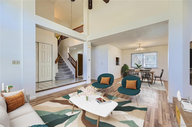 living room featuring stairway, a textured ceiling, baseboards, and wood finished floors